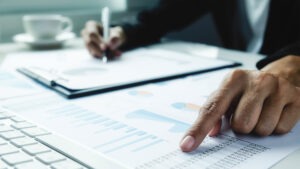 Mann sitzt am Schreibtisch. Und kalkuliert die Kosten für bestehende Software Lizenzen durch.